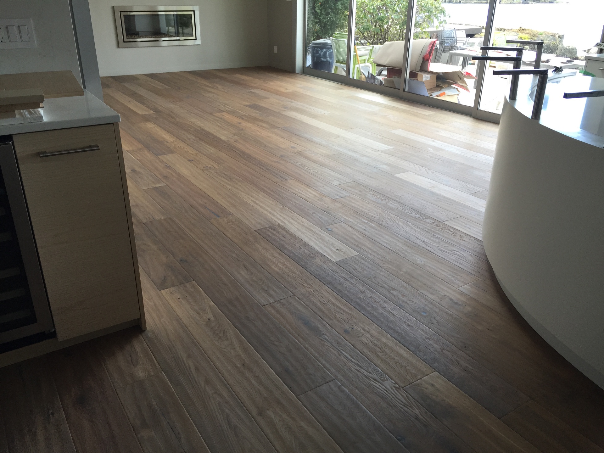 Gibsons House — character white oak hardwood in open living area with fireplace and patio doors