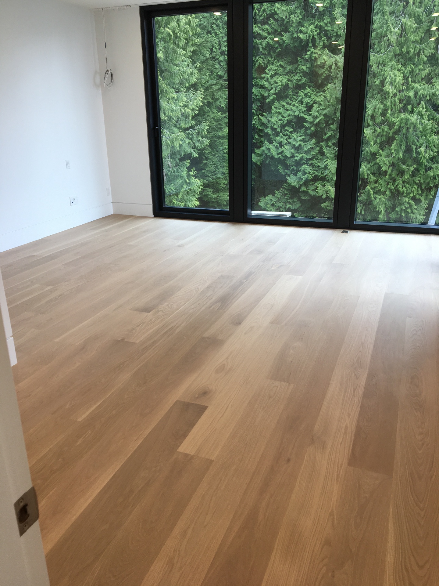 West Vancouver Home — site-finished white oak hardwood in bedroom with floor-to-ceiling forest-view windows