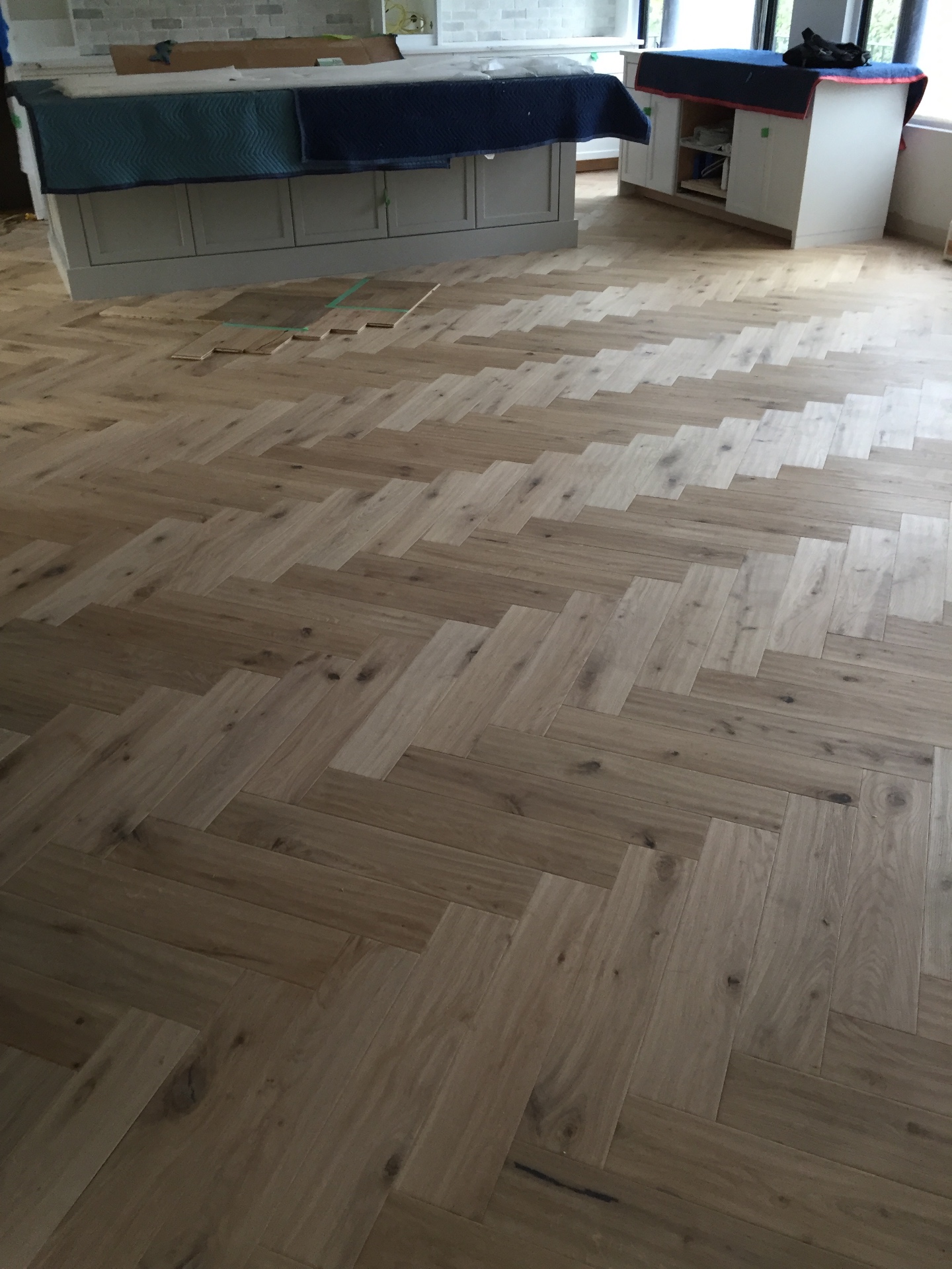 Vancouver Loft — white oak herringbone installation in progress beside custom kitchen island