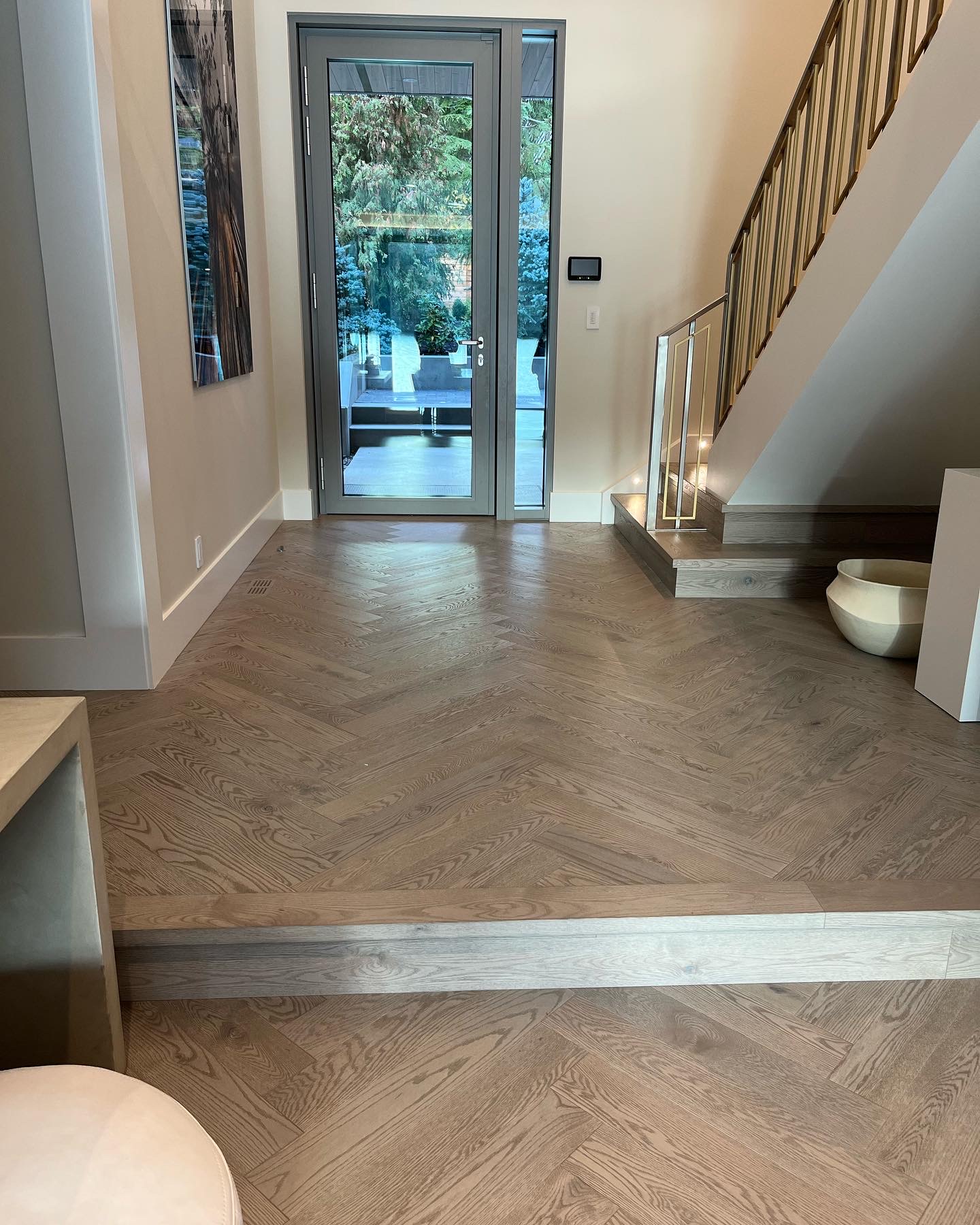 Whistler Home — white oak herringbone entryway with glass door and brass-railed staircase