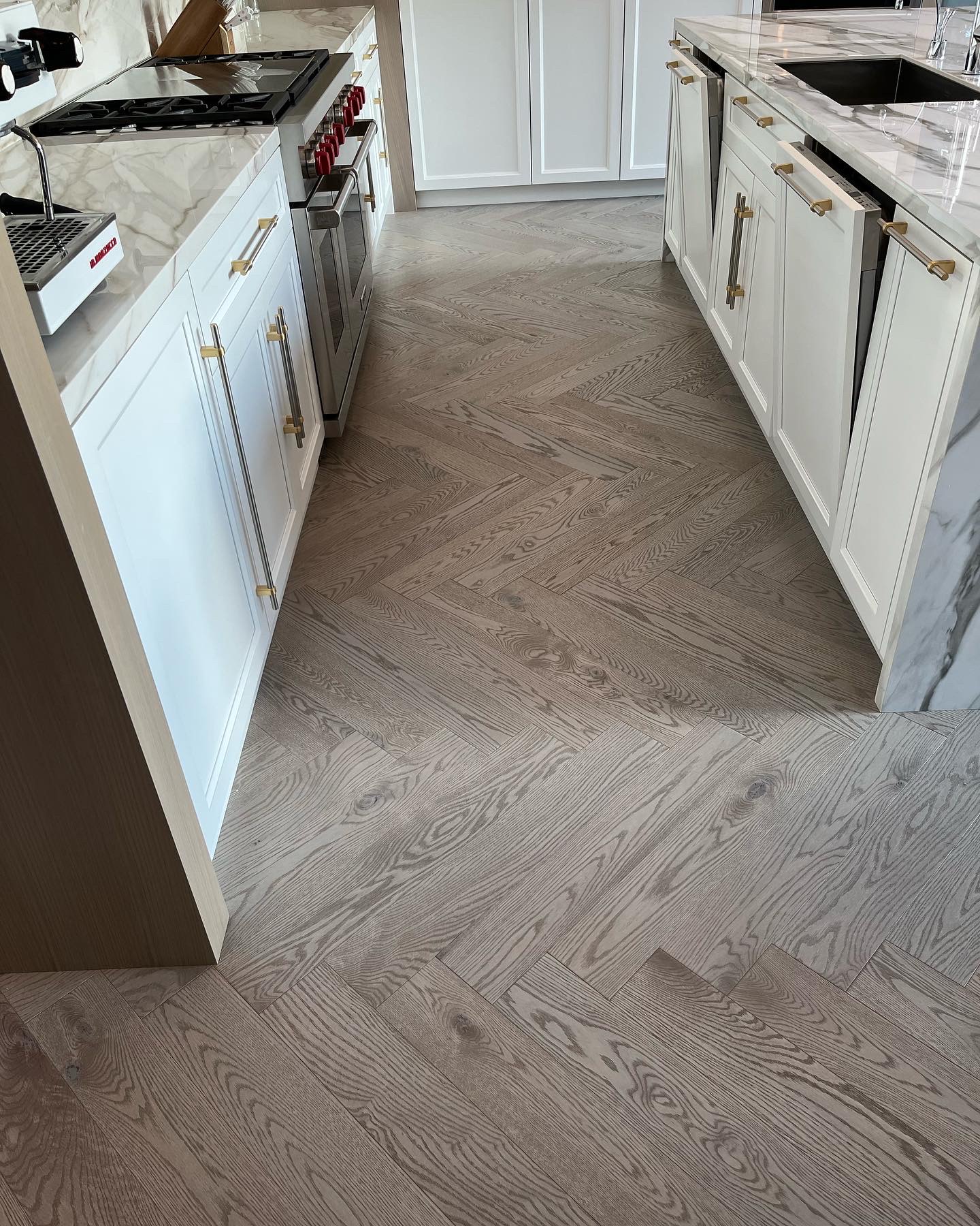 Whistler Home — character-grade white oak herringbone between marble kitchen islands