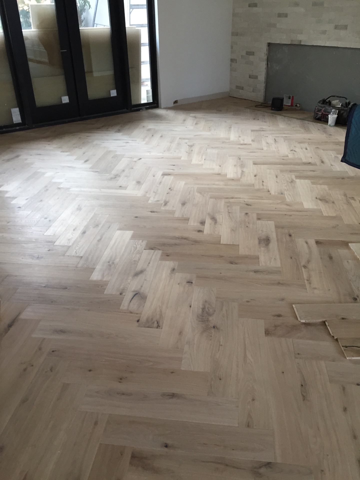 Vancouver Loft — character-grade white oak herringbone hardwood by black-framed patio doors