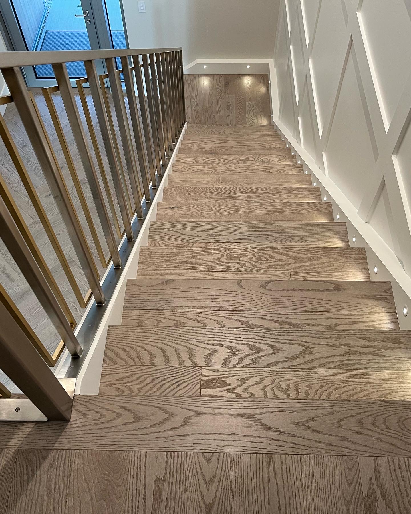 Whistler Home — solid white oak stair treads with brass railings and diamond-panelled accent wall