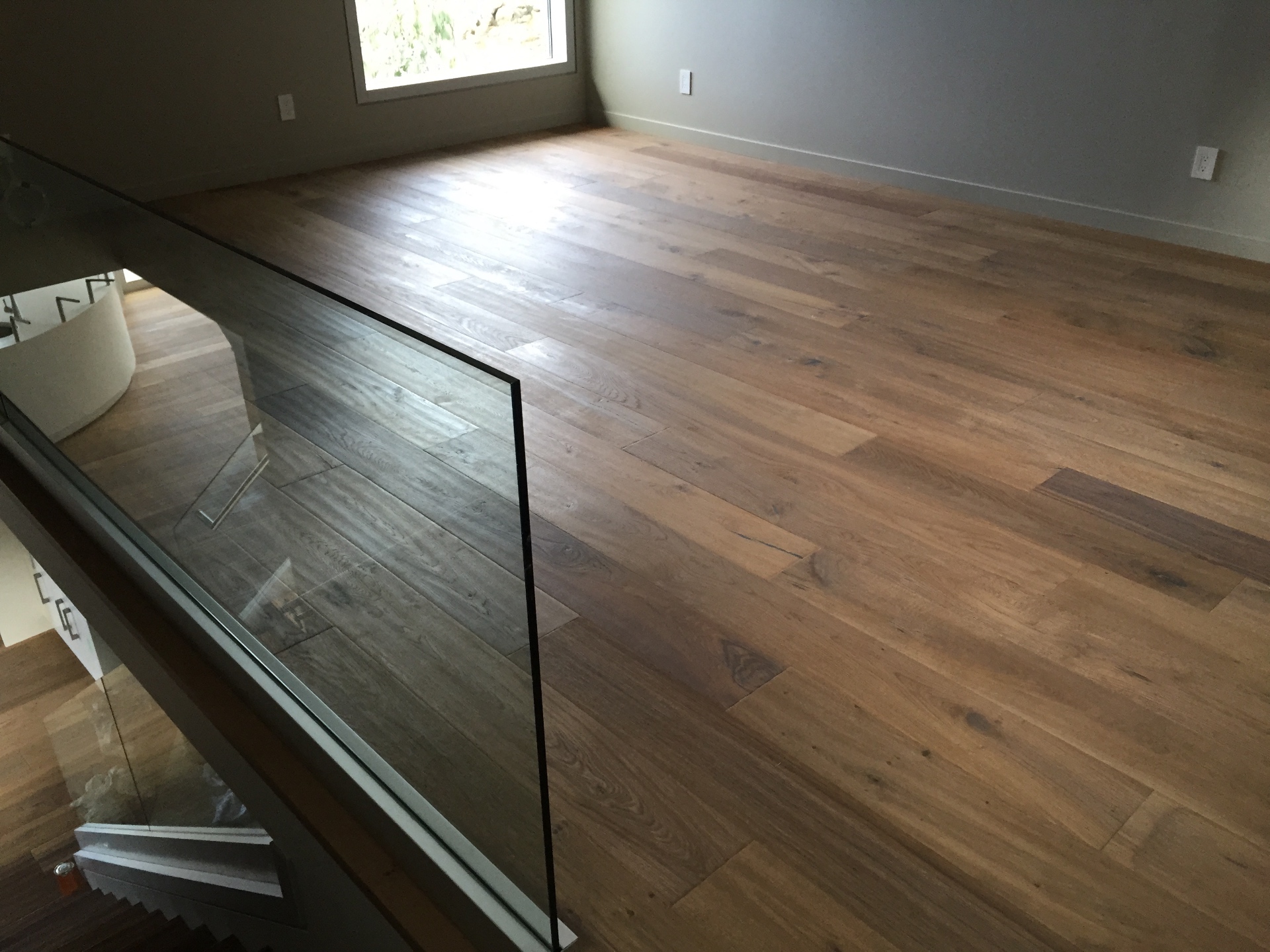 Gibsons House — second-floor hardwood landing with glass railing overlooking entry