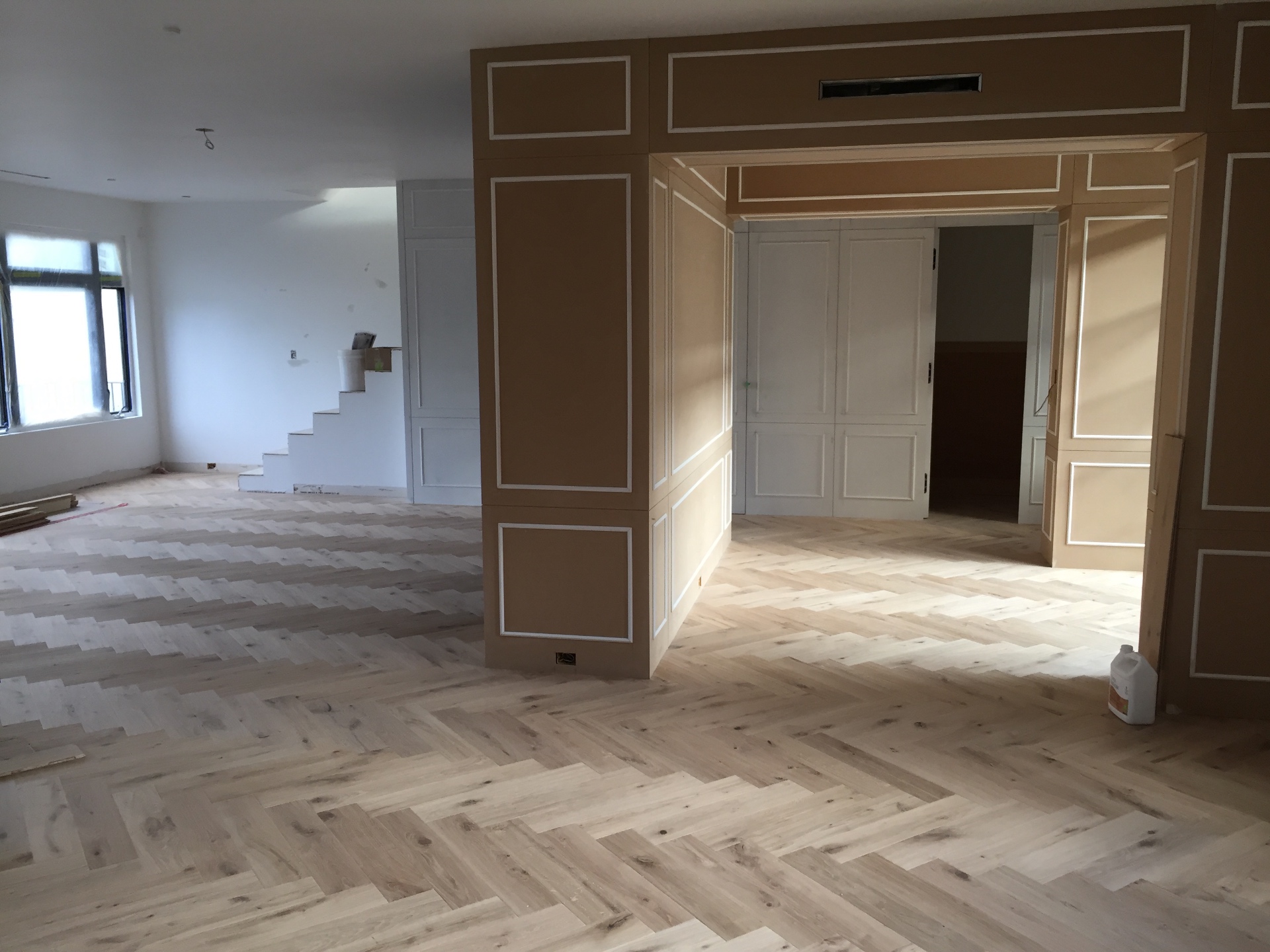 Vancouver Loft — character white oak herringbone hardwood through main living area with panelled feature wall