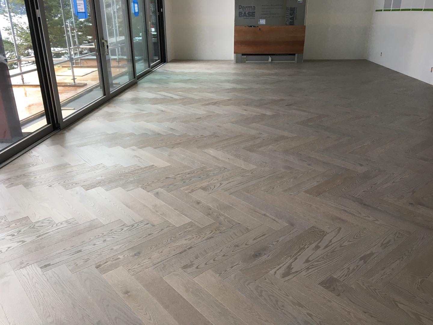 Whistler Home — wide-plank white oak herringbone installation by sliding glass doors with mountain view