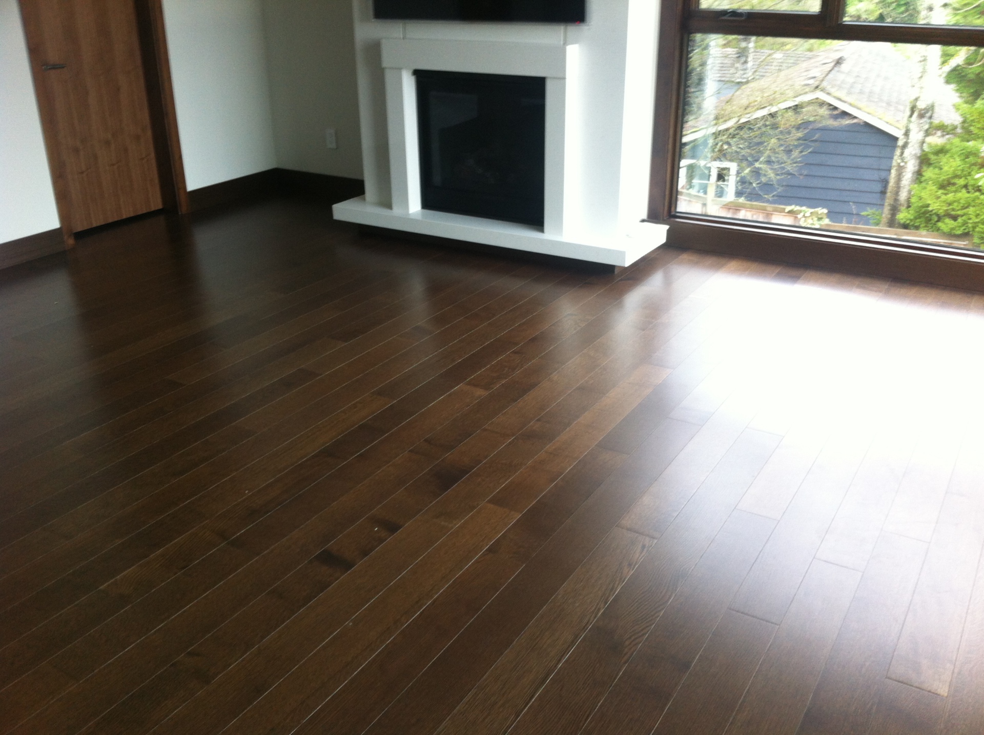 West Vancouver Home — Vintage walnut hardwood flooring in living room with white fireplace and garden view