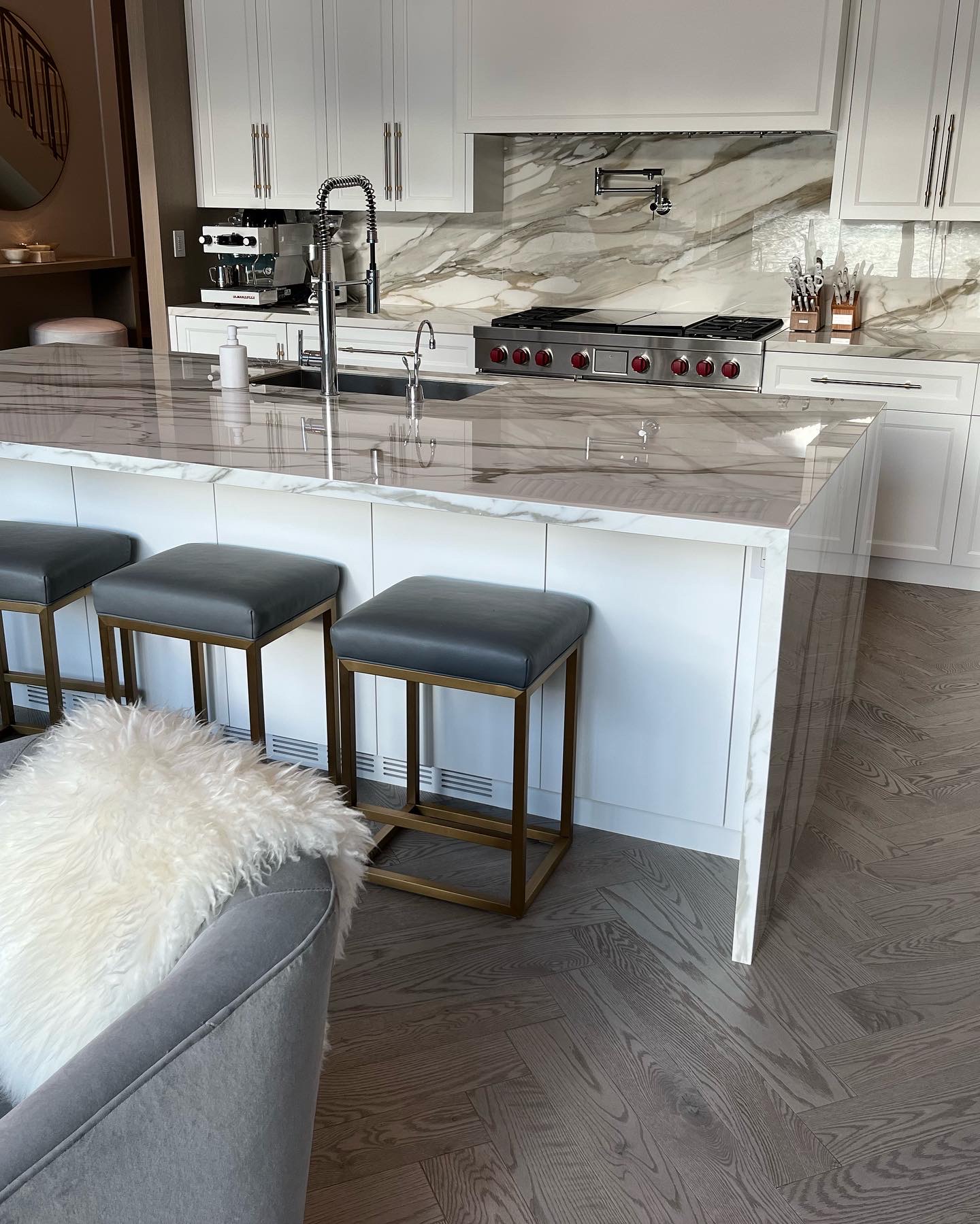 Whistler Home — Mirage white oak herringbone hardwood in marble kitchen with brass barstools